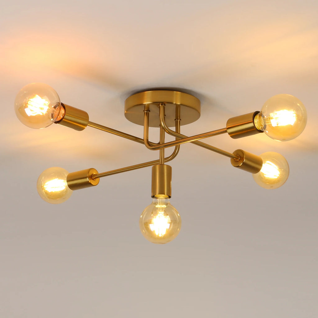Modern semi-flush ceiling light fixture with a gold brass finish and five exposed filament light bulbs, shown illuminated against a neutral ceiling background.