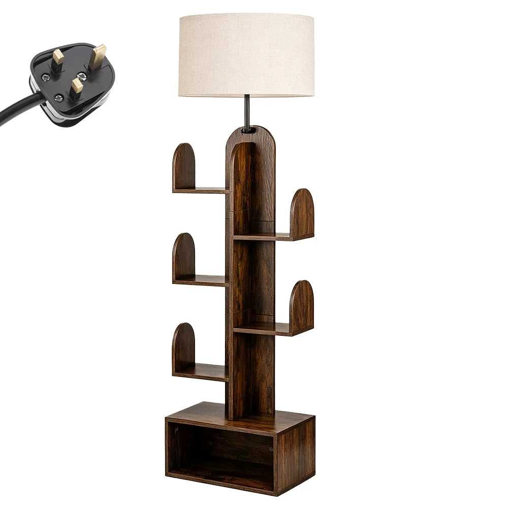 A modern dark brown wooden floor lamp with an arched trunk design, five tiered shelves, and a cylindrical off-white fabric drum shade. A black three-pin power plug is shown in the top-left corner against a solid white background.