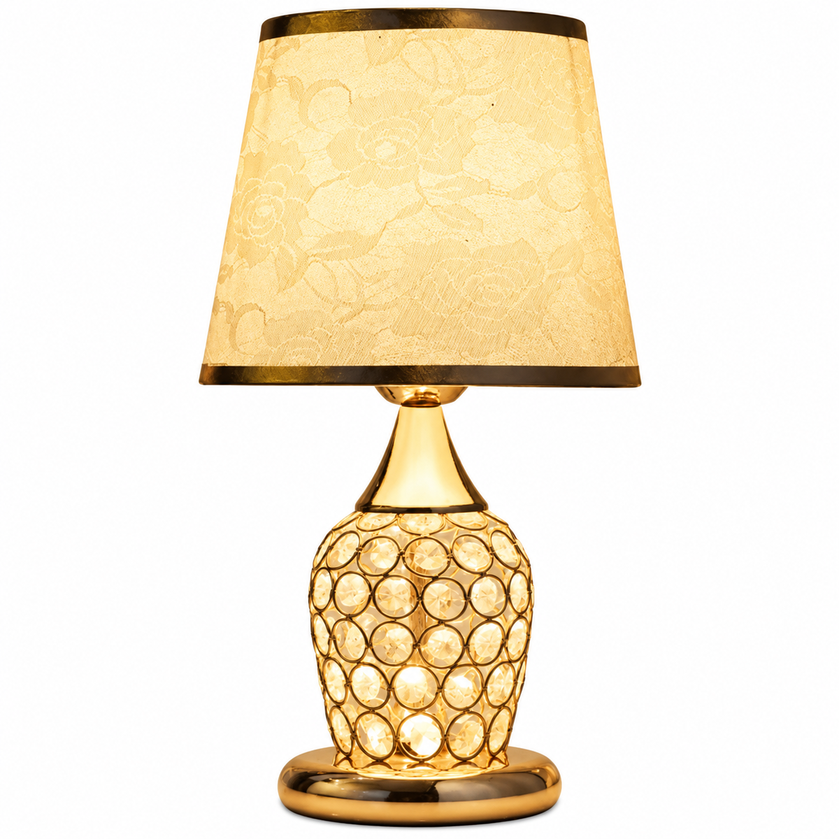 A table lamp with a warm gold-finished base featuring a circular crystal-like pattern, a matching gold-toned neck and base, and a tapered beige fabric shade with a subtle floral pattern and gold trim.