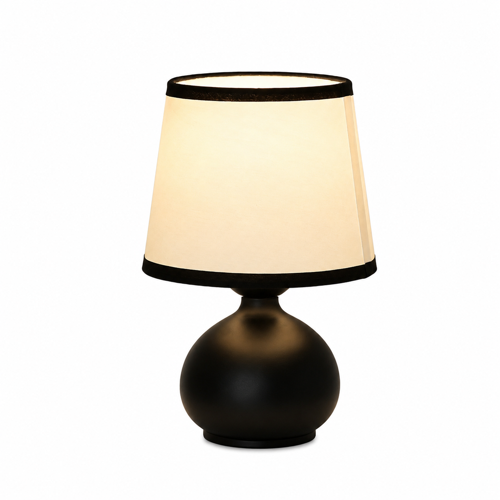 A modern table lamp with a matte black spherical base and a tapered cream fabric shade with black trim, shown against a plain white background.