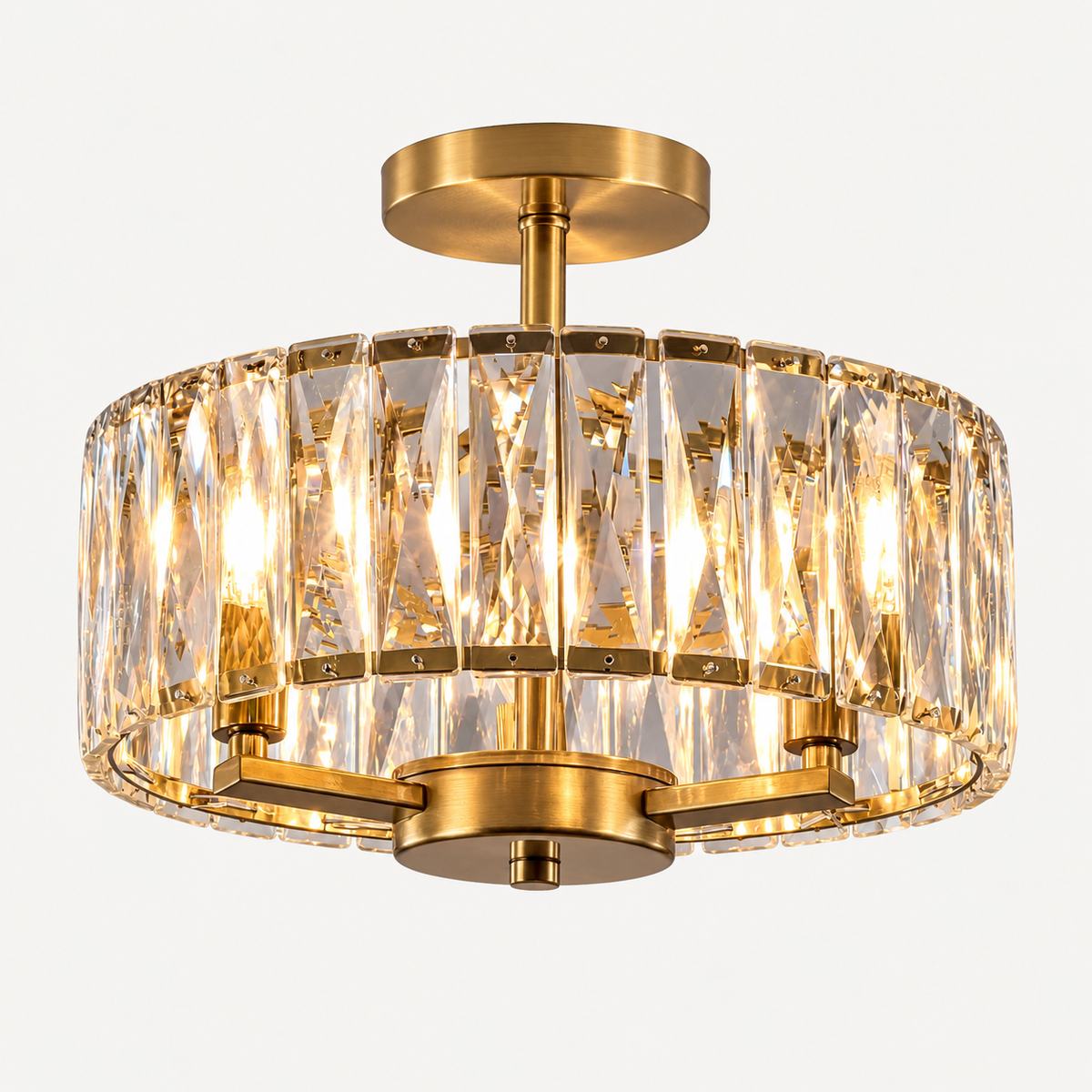 A modern semi-flush mount ceiling light fixture with a brushed gold metal frame and clear cylindrical crystal prisms, shown illuminated against a plain white background.