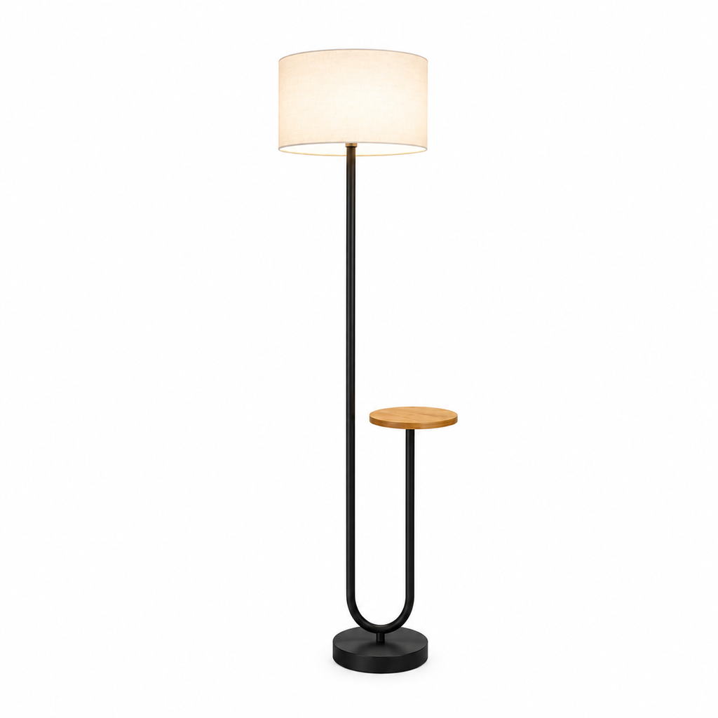 A modern floor lamp with a black metal frame, a small round wooden side table integrated into the stand, and a warm white fabric drum shade, shown against a plain white background.