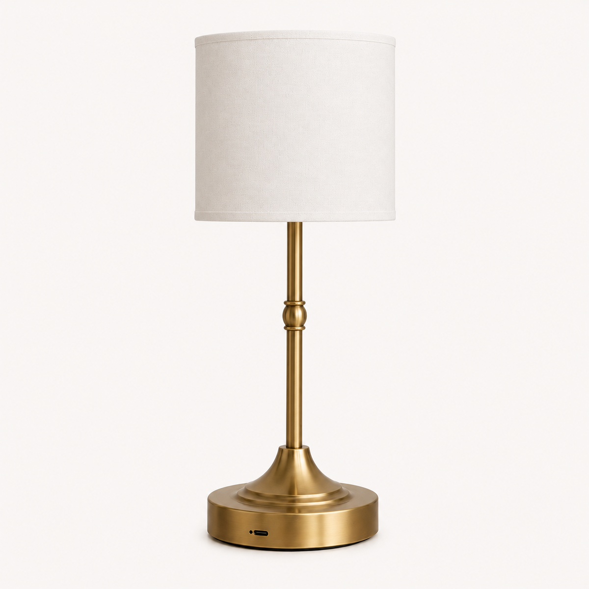 Modern brass table lamp with white linen drum shade and round base.