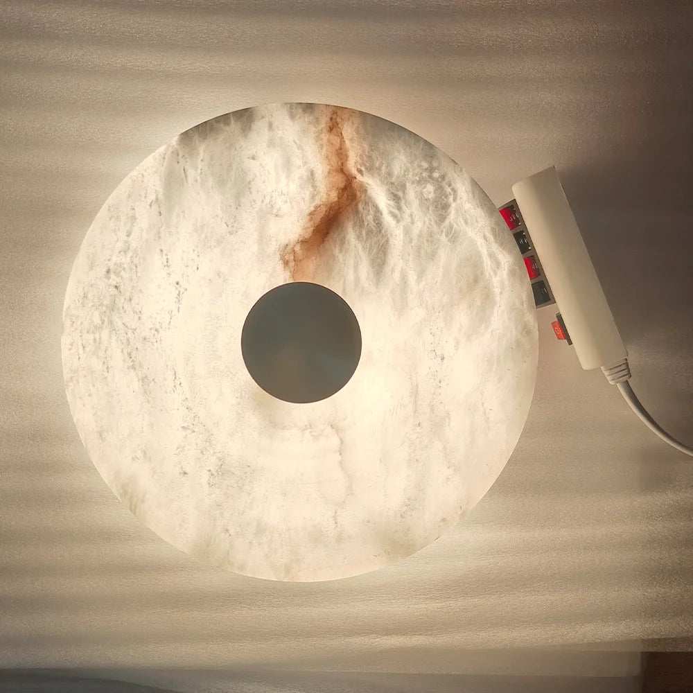 Round marble lamp with a power strip on a textured surface