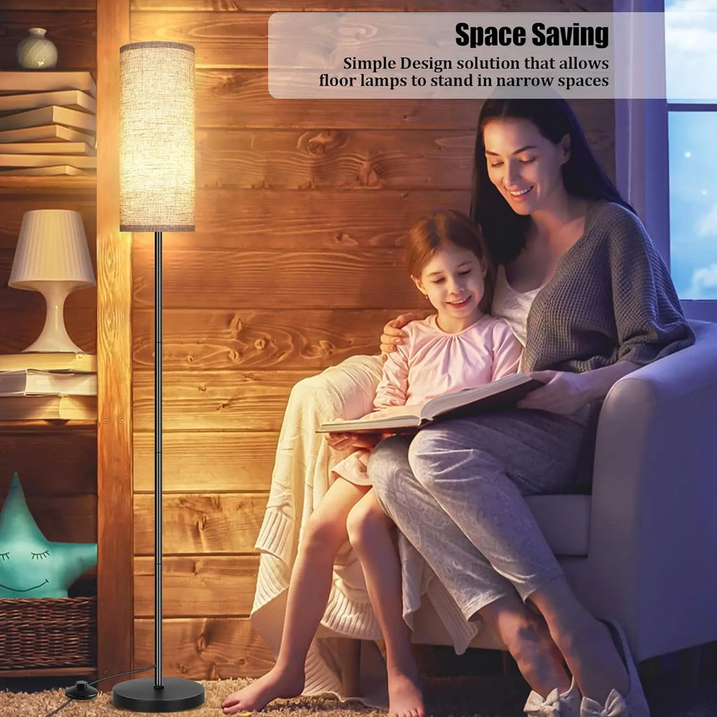 Woman and child reading a book next to a floor lamp in a cozy room.