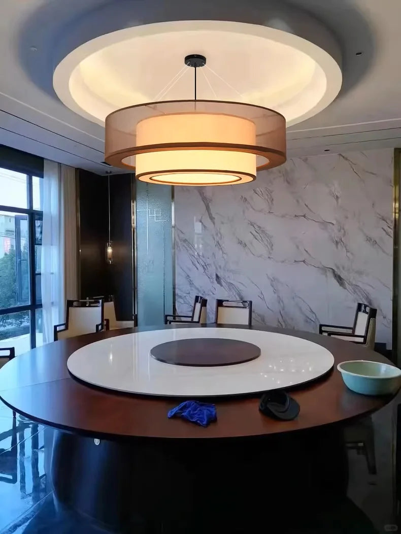 Modern dining room with a round wooden table and pendant light fixture.