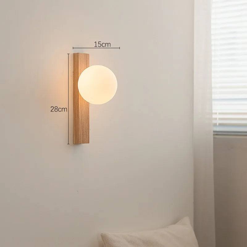Wall-mounted light fixture with wooden frame and glass shade on a neutral wall.