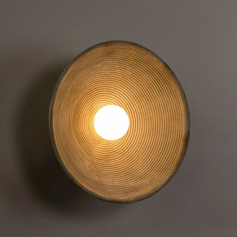 Cylindrical light fixture with textured surface and glowing center on a dark background