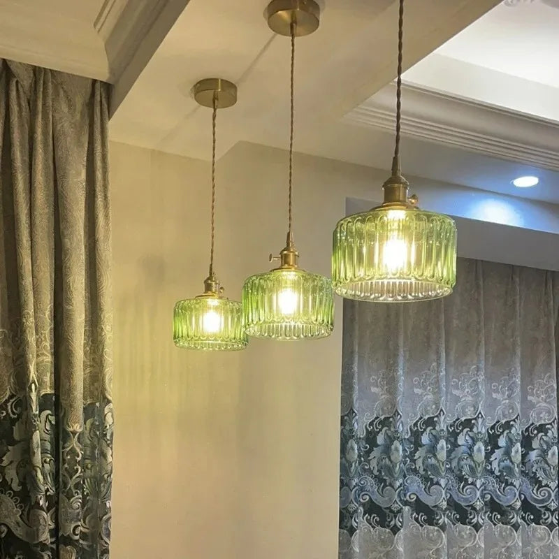 Three green pendant lights hanging in a room with curtains.