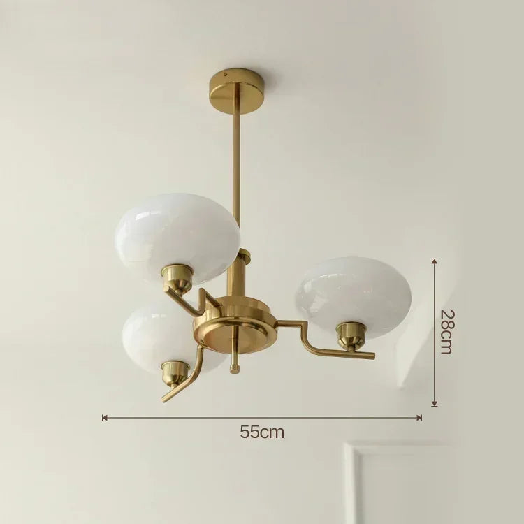 Gold ceiling light fixture with white glass shades and dimensions on a plain background
