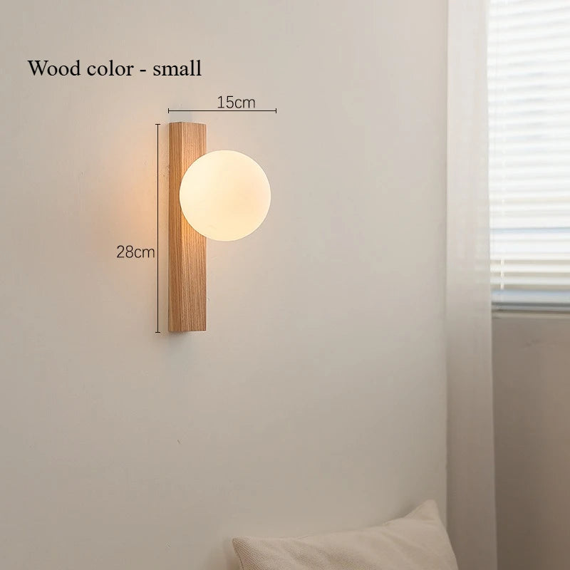 Wall-mounted light fixture with wooden frame and glass shade on a neutral wall.