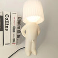 White lamp shaped like a person with books in the background