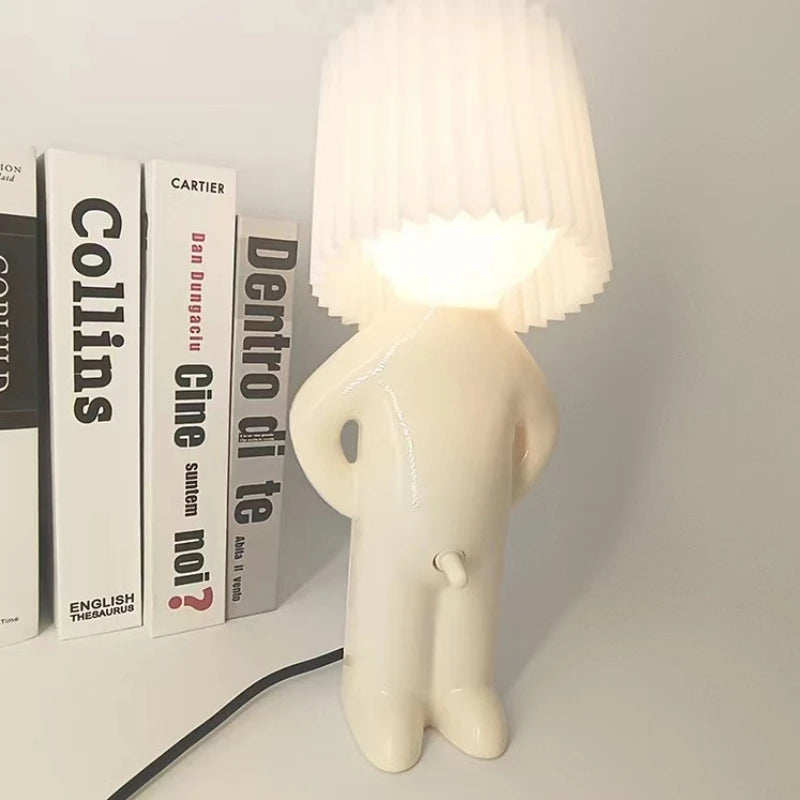 White lamp shaped like a person with books in the background