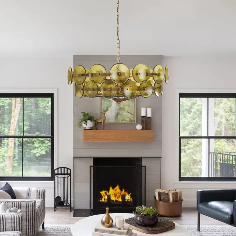 Modern living room with a gold chandelier, fireplace, and large windows.