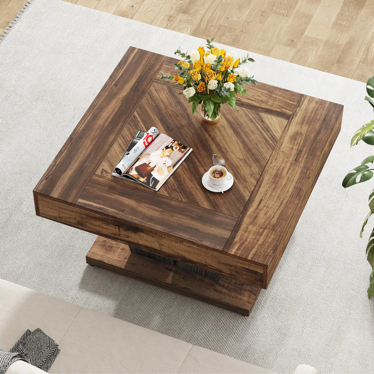Wooden coffee table with a magazine, cup, and flower arrangement on a light-colored rug.