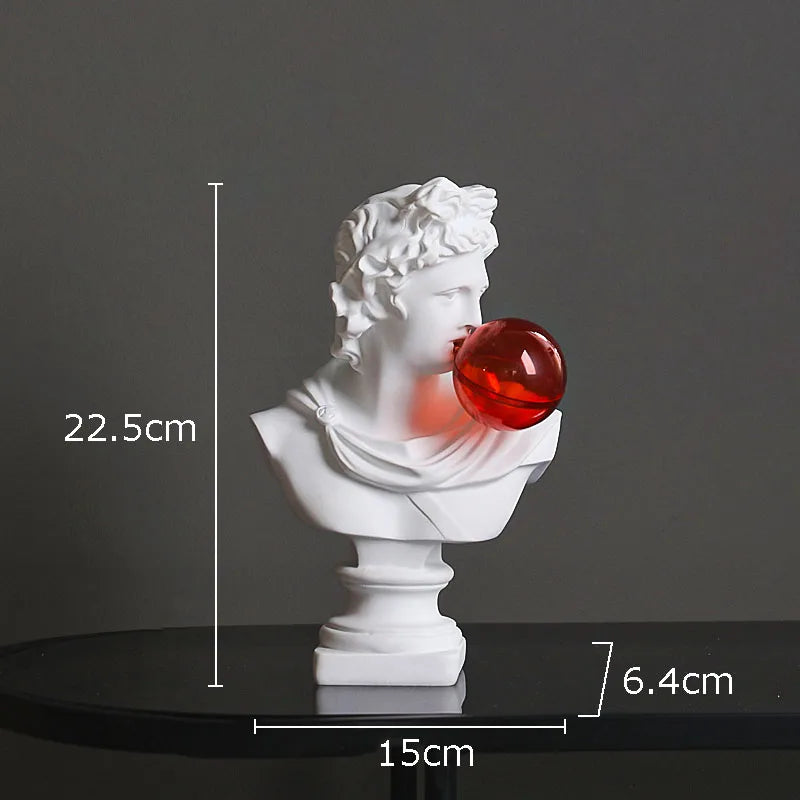 White classical-style bust sculpture light blowing a red bubblegum bubble, shown on a dark surface with dimension labels 22.5 cm height, 15 cm width, and 6.