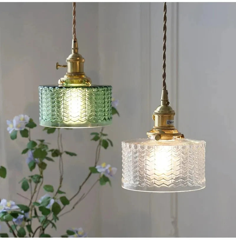 Two hanging pendant lights with textured glass shades on a neutral background.