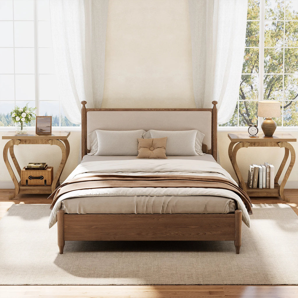 Wooden bed with beige bedding in a bright bedroom with large windows.