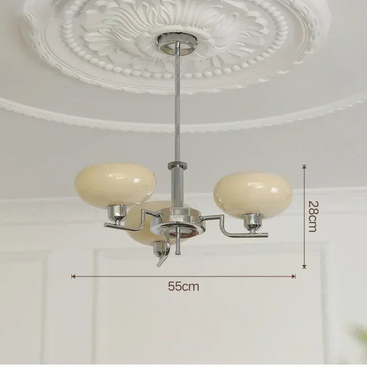 Ceiling light fixture with three cream-colored glass shades on a white ceiling.