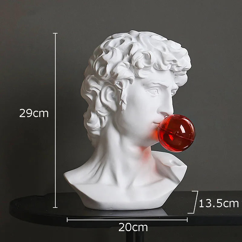 White classical-style male bust sculpture light with a glossy red bubblegum bubble protruding from its mouth, shown on a dark surface against a dark gray background with overlaid dimensions: 29 cm height, 20 cm width, and 13.5 cm bubble diameter.