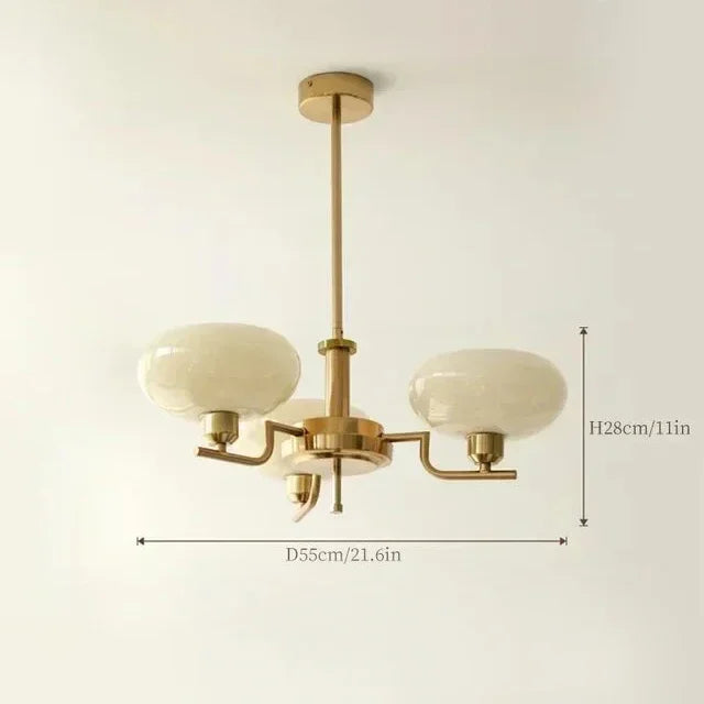 Gold chandelier with white glass shades on a light beige background